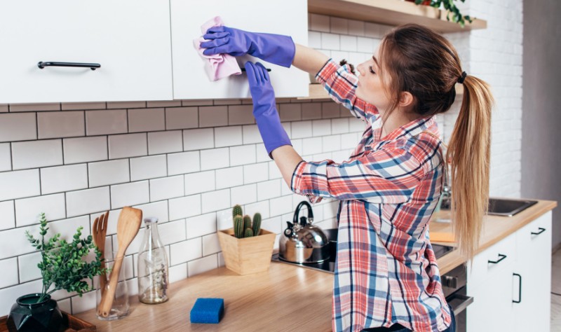 A woman is cleaning kitchen cabinets