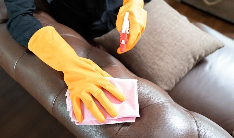 cropped picture of a person wiping a leather couch with a cloth