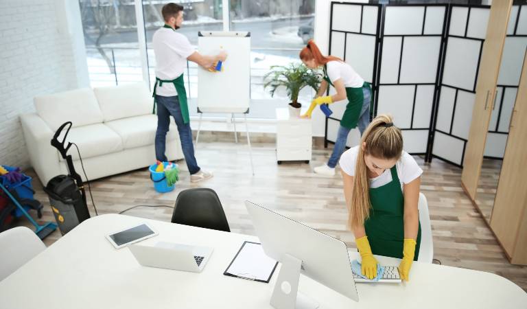 one man and two women cleaning inside a office