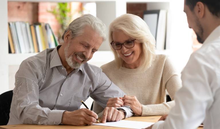 Old man and woman signing a paper and smiling