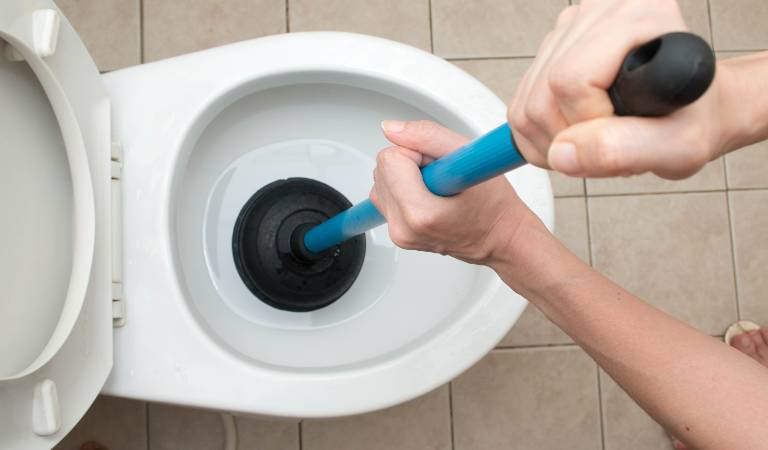 Hand of a man cleaning toilet.