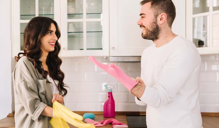 One couple smiling and wearing glove to clean their home.