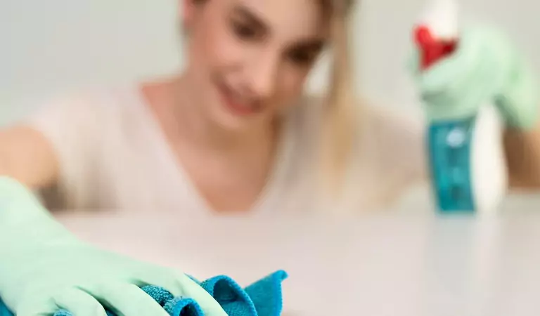 young woman with a cleaning spray disinfecting a surface