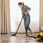 Woman in check shirt and jeans using vacuum cleaner to clean her floor.