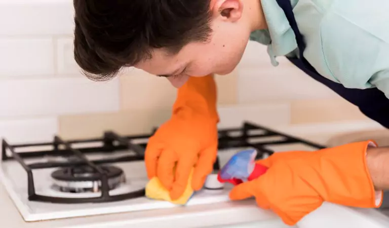 young man cleaning the stove top