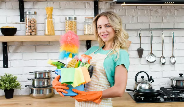 woman with some cleaning supplies inside of a kitchen