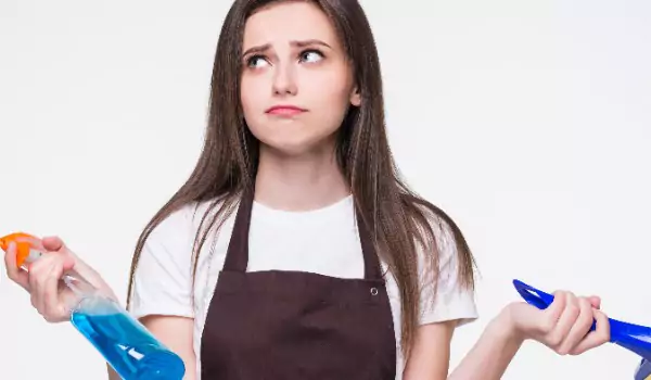 woman looking worried and holding some cleaning essentials in hands