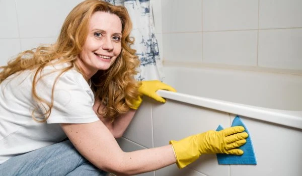 Side view of woman cleaning the bathtub