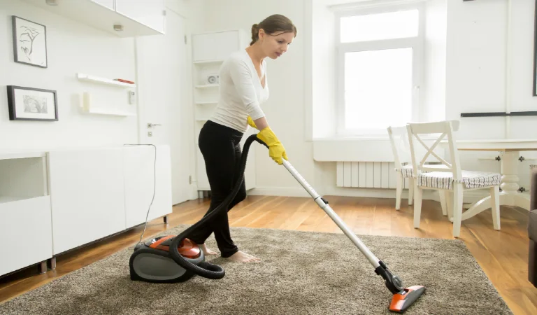 Woman in casual wear vacuum cleaning the carpet