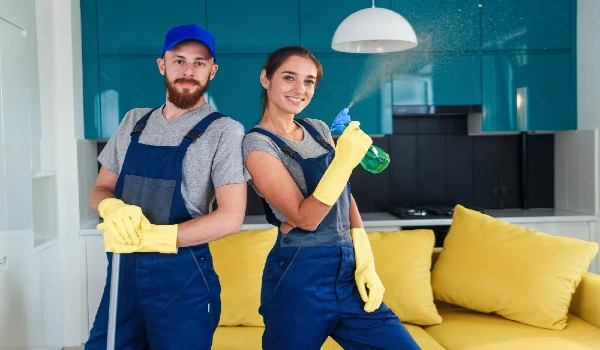 Professional cleaners holding cleaning supplies in a living room