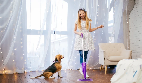 Young woman cleaning room with dog