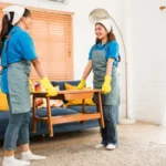 Two asian women housekeeper moving low table together before cleaning wooden floor concept