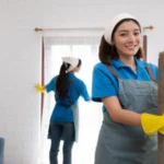 Young women cleaning maid in uniform and rubber gloves are cleaning the room fold up carpet