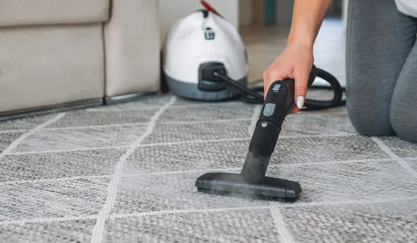 Woman cleaning carpet with a steam cleaner