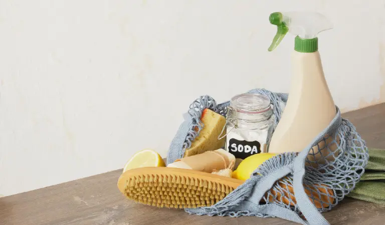 Eco cleaning kit in mesh bag on the table spray bottle soda lemon and natural cleaning sponges