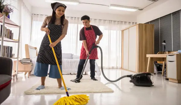 Happy asian young couple using vacuum cleaner and mop to clean home bedroom