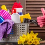 Showing thumbs up and cleaning products in a basket with flowers beside it